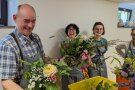 Ein Mann und zwei Frauen betrachten ihre Blumensträuße.