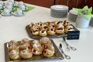 Kaffeetafel mit weißem Geschirr und Windbeuteln, gefüllt mit Erdbeeren und Sahne.