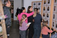 Drei FRauen, zwei Kinder und ein Mann stehen vor den Jahrgangsfotos aus 100 Jahren Schulgeschichte.