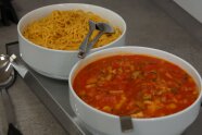 Auf einer Warmhalteplatte stehen zwei Schüsseln mit Tagliatelle und Ratatouille.